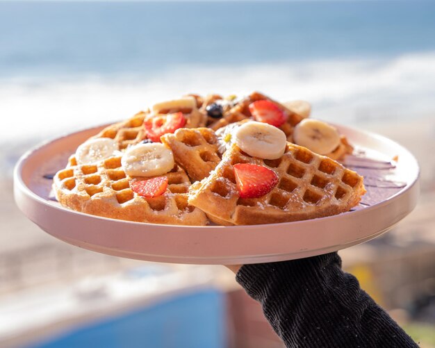 Foto waffles deliciosos com morangos, banana e mel, estilo bruch americano.