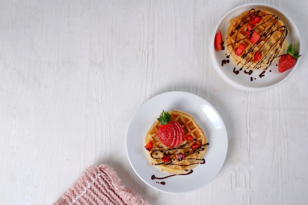 Waffles con fresa sobre fondo blanco.