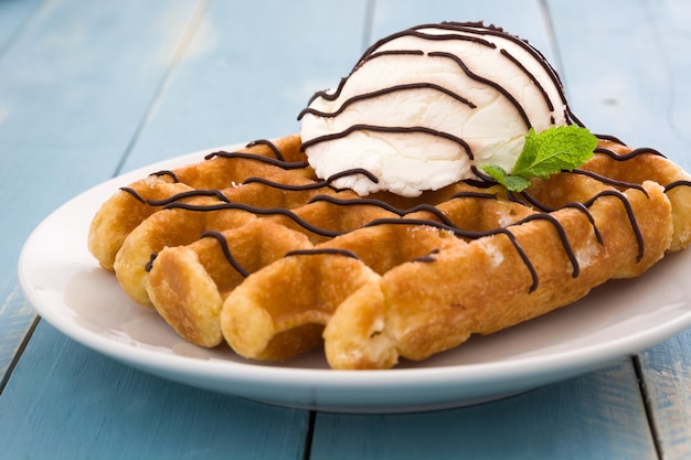 Waffles con helado en la mesa de madera azul