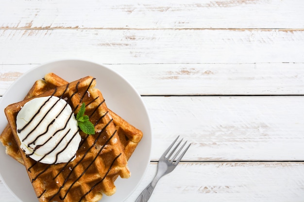 Waffles con helado en la mesa de madera blanca