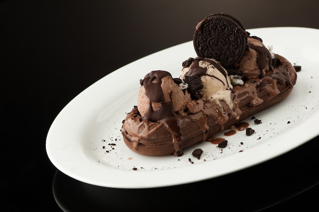 Waffles y helado en un plato sobre un fondo oscuro