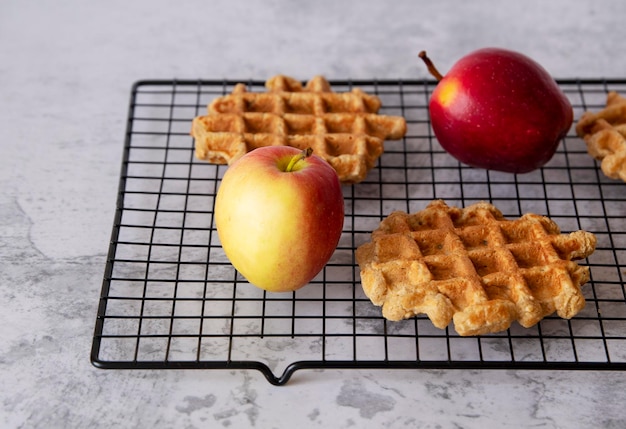 Waffles de manzana caseros a la parrilla con manzanas rojas sobre un fondo de textura gris Vista lateral macro