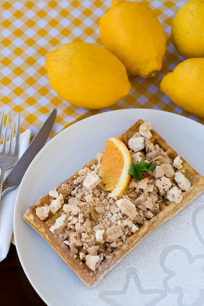 Waffles con merengue, rizos de limón y rodajas de naranja para el desayuno.