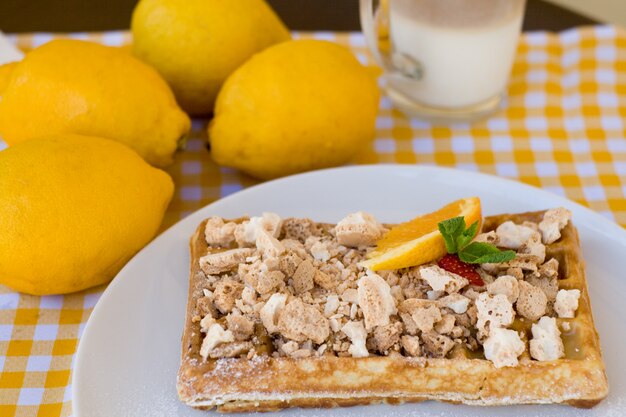 Waffles con merengue, rizos de limón y rodajas de naranja para el desayuno.