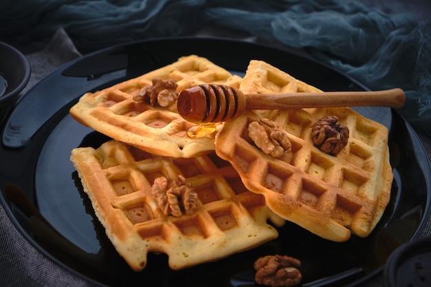 Waffles con miel sobre una superficie oscura, close-up