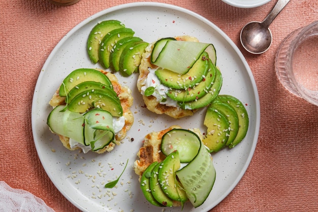 Waffles con queso crema, aguacate y pepino en un plato