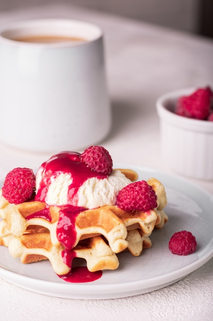 Waffles recém-assados com calda de framboesa e sorvete no prato