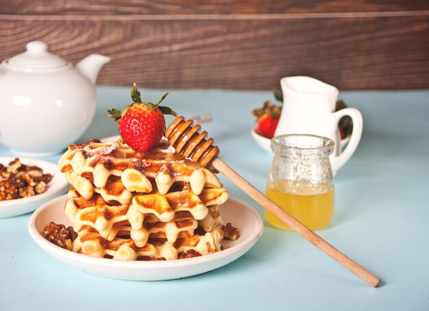 Foto waffles recién hechos en casa con fresas y miel.