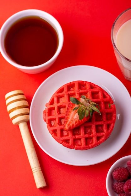 Waffles rojos saludables con frutas, miel y leche sobre fondo rojo con diferentes ángulos