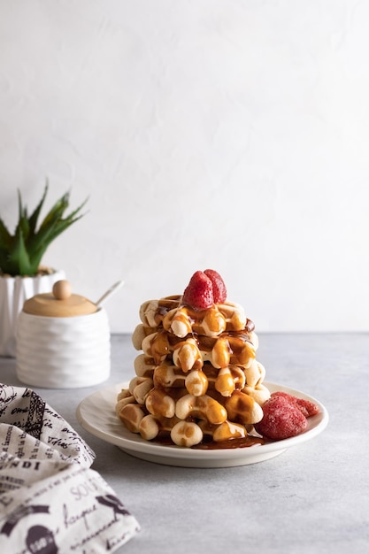 Waffles vieneses con fresas y jarabe de caramelo sobre un fondo claro