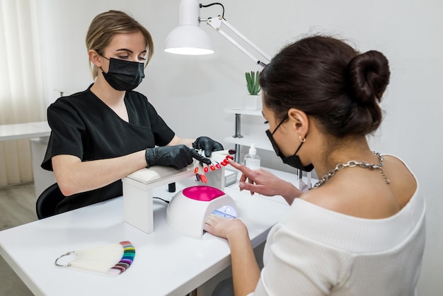 Wahl der Nagelfarbe Ein junges Mädchen wählt die Farbe ihrer Nägel in einem Schönheitssalon Schönheit und Gesundheit der Nägel Maniküre und Client in einem Nagelstudio