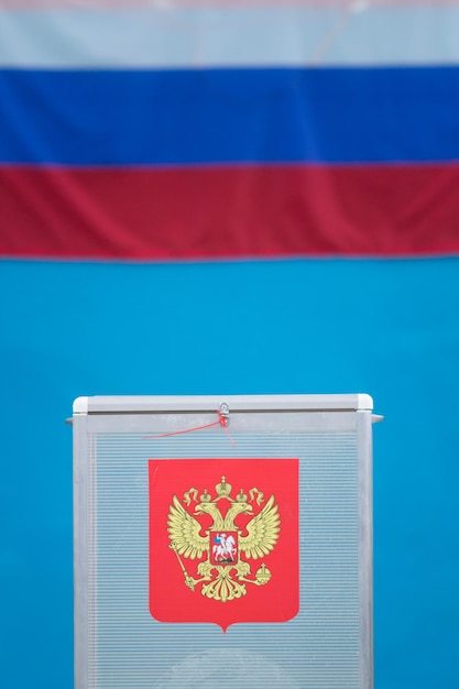 Wahlbox für Präsidentschaftswahlen mit Stimmzetteln vor russischer Flagge