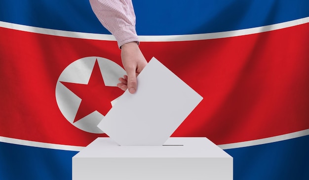Wahlen in Nordkorea Wahlkonzept Eine Hand wirft einen Stimmzettel in die Wahlurne