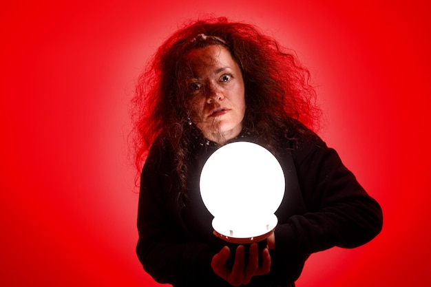 Wahrsager hält einen leuchtenden Ball in ihren Händen Roter Hintergrund
