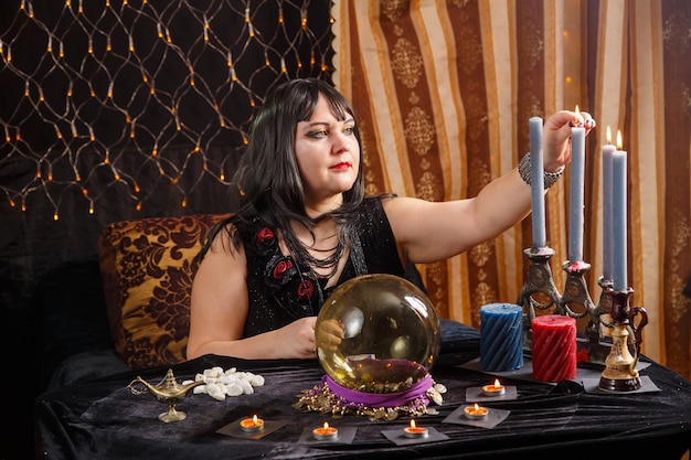 Wahrsagerin, brünette Frau im Zaubersalon zündet Kerzen an, bevor sie mit der Arbeit beginnt