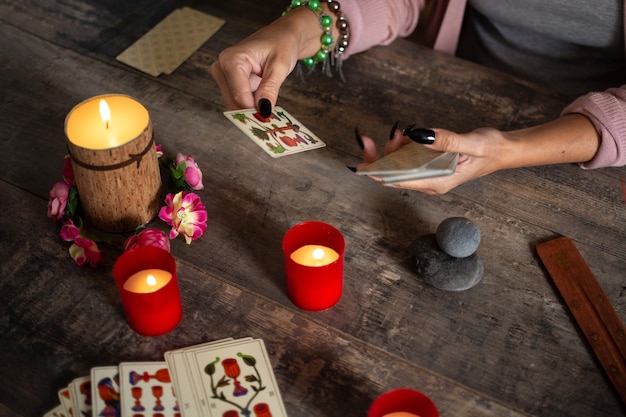 Wahrsagerin liest eine Zukunft durch Tarotkarten auf rustikalem Tisch