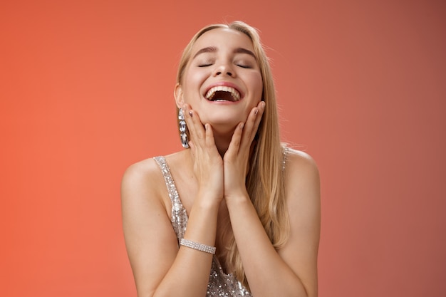 Waistup alegre logrado encantadora rica mujer rubia en elegante vestido de noche plateado