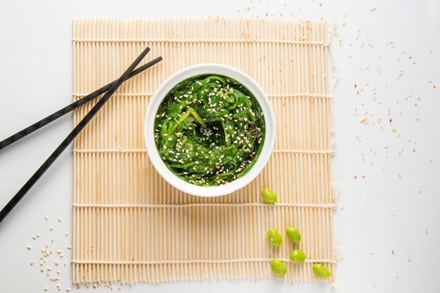 Wakame en el tazón blanco y palillos