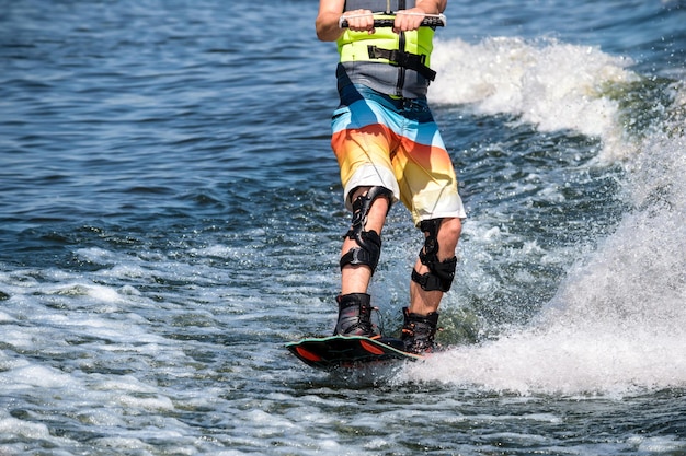 Wakeboard. sportlerfüße auf dem brett auf der welle. spezialausrüstung für fixierte knie