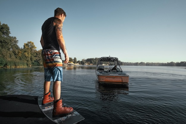 Wakeboard, wakeboarder de homem em pé no cais esperando os barcos de wakeboard. manhã