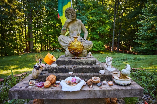 Wald mit Plattform für kleine tibetisch-mongolische buddhistische Steinstatue und Spenden