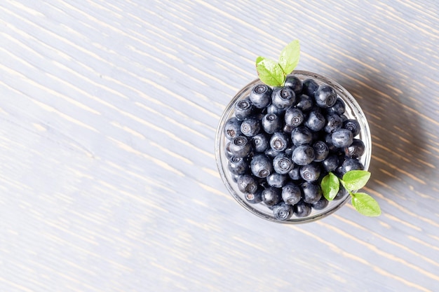 Waldblaubeeren in Schüssel auf grauem Holztisch Superfood Draufsicht Kopierbereich