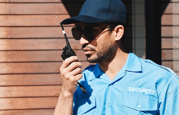 Walkietalkie de guarda de segurança e oficial de segurança ao ar livre para patrulha de proteção e comunicação Trabalhador sério e de prevenção do crime com uniforme de óculos de sol e rádio na cidade