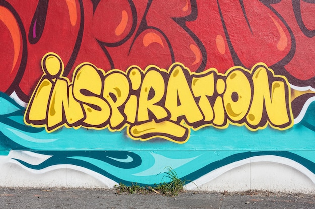 Wand mit farbenfrohen Graffiti und Zeichnungen, die das Wort Inspiration mit rotem Ye hervorheben