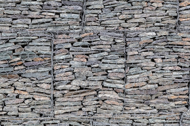 Wand mit kleinen grauen Steinen hinter einem Metallgitter ausgekleidet