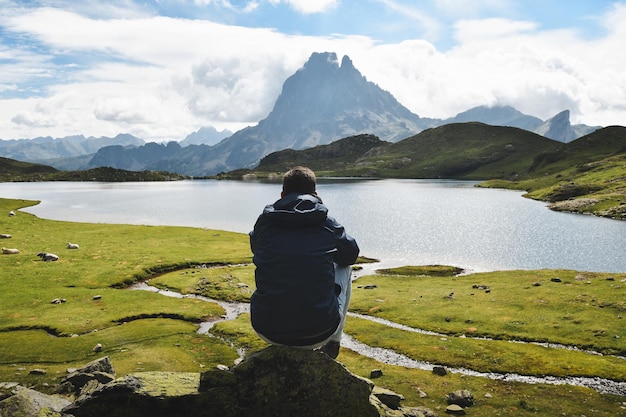 Wanderer, der auf einem Felsen sitzt und einen großartigen Panoramablick auf den Lac Gentau Lacs d'Ayous hat