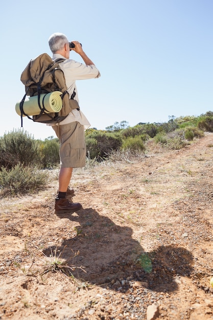 Wanderer, der durch Ferngläser auf Landspur schaut