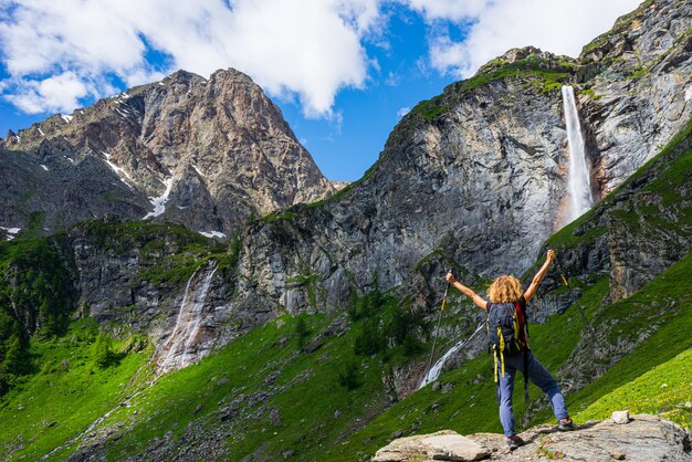 Wanderer, der Wasserfall auf Berg betrachtet