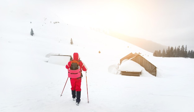 Wanderer, die an einer alten, schneebedeckten Hütte vorbeigehen