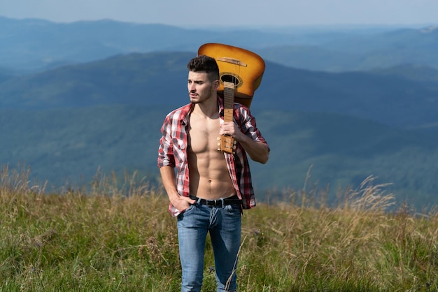 Wanderer Mann mit Gitarre Blick auf Berge Blick Wochenende im Naturcampingurlaub