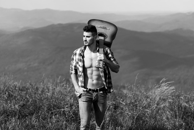 Wanderer Mann mit Gitarre Blick auf Berge Blick Wochenende im Naturcampingurlaub