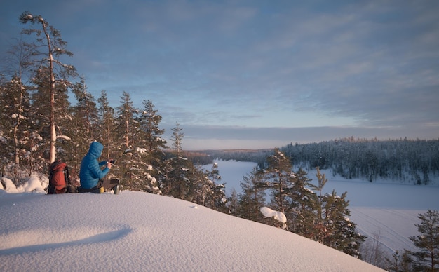 Wanderer ruht sich in einem malerischen schneebedeckten Gebiet aus Der Mann benutzt ein Mobiltelefon