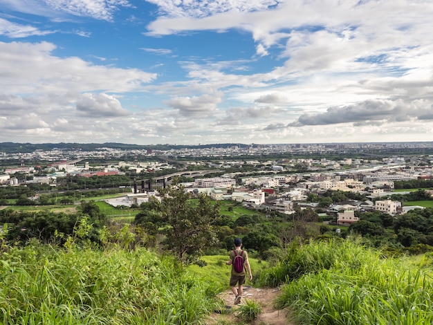 Wanderer und Blick auf die Stadt vom schönen Berg. Blauer Himmel und grüne Wiese