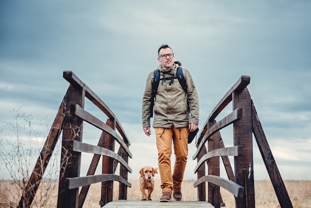 Wanderer und Hund auf Holzbrücke