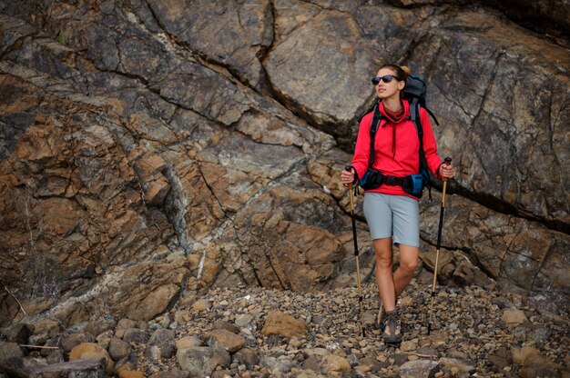 Wanderermädchen in der Sonnenbrille mit Rucksack in den Bergen