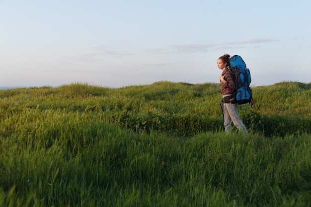 Wanderermädchen reist mit einem Rucksack auf der Landschaft