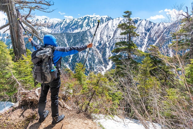 Foto wanderermann-grifftrekkingstock und ausgebreitete hand, wenn sie schneebergkette am standpunkt sehen.