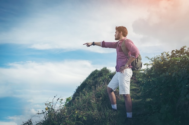 Wanderermann mit dem Rucksack, der herauf die Spur mit schönen Bergspitzenansichtlandschaft geht