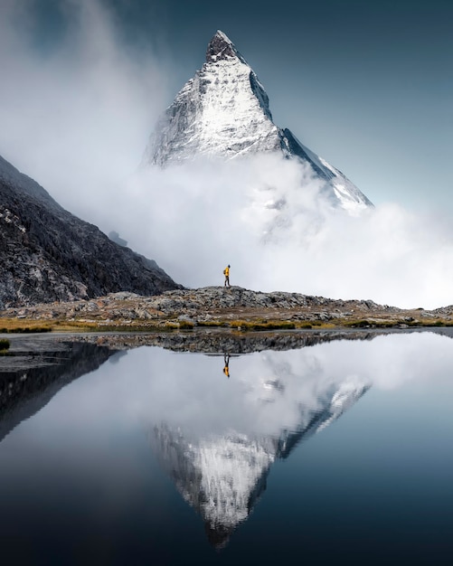 Foto wanderermann wandert allein durch die unglaublichen schweizer alpen mit dem matterhorn im hintergrund dazwischen