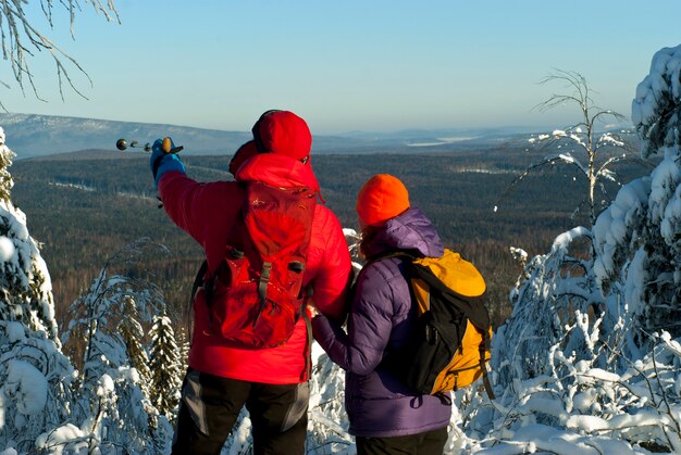 Wandererpaar stehen im Winter mit dem Rücken zum Betrachter auf dem Gipfel des Berges