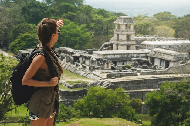 Wanderfrau mit einem Rucksack, der alte Maya-Ruinen betrachtet