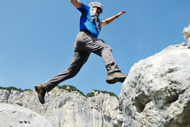 Wandern des Mannes, der über die Berge zum Erfolg springt