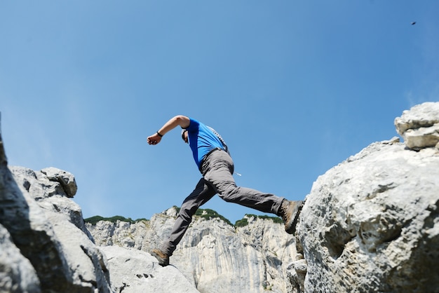 Wandern des Mannes, der über die Berge zum Erfolg springt