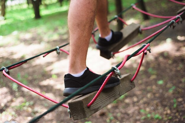 Wandern im jungen Mann des Seilparks im sicheren Gang.