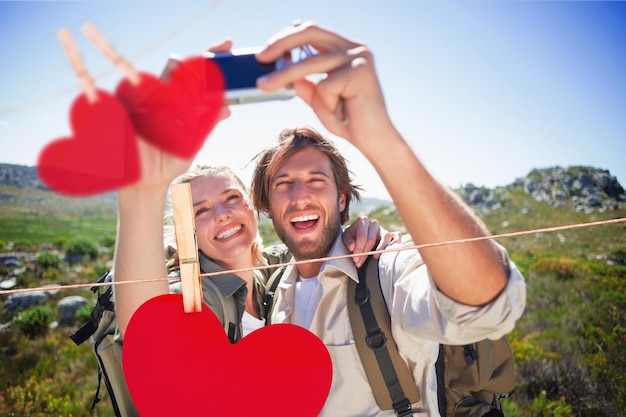 Wanderpaar, das auf Berggelände steht und ein Selfie gegen Herzen macht, die an einer Linie hängen