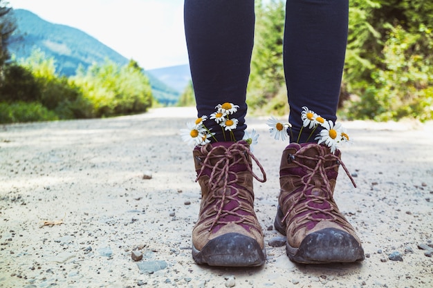 Wanderschuhe Nahaufnahme. Mädchentouristin in Stiefeln mit Gänseblümchen